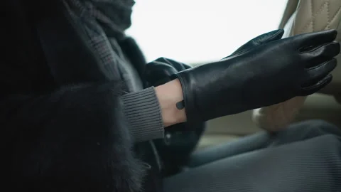 Close up of woman adjusting black leather gloves inside car interior with Stock Footage 346734553