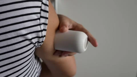 Close-up of a woman applying a continuous glucose monitoring (CGM) sensor t.. Video stock 343941286