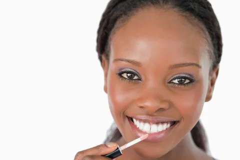 Close up of woman applying lip gloss against a white background Stock Photos