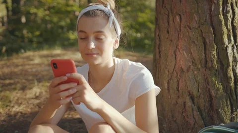 Close up woman with backpack use smartphone sitting near tree in the fall forest Stock Footage 115201627