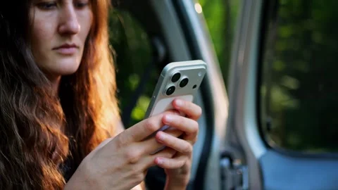 Close-up of a woman checking her smartphone in a car, highlighting... Видео 340290942