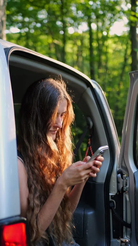 Close-up of a woman checking her smartphone in an SUV during... Видео 340290997