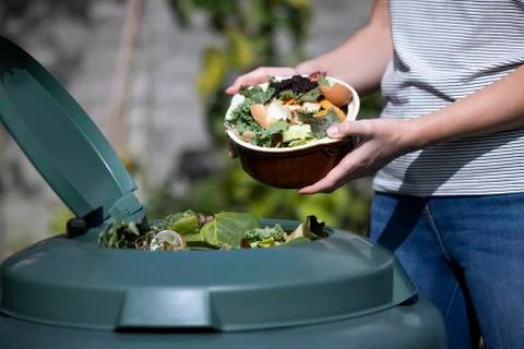 Close Up Of Woman Emptying Food Waste Into Garden Composter At Home Stock Photos