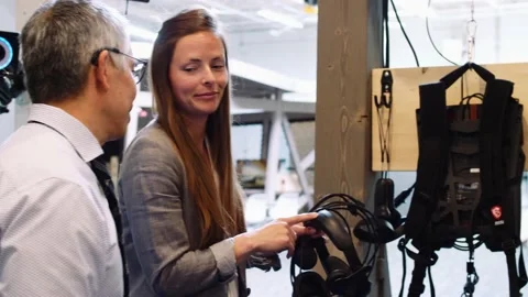 Close up of woman explaining features of virtual reality gear to colleagues Stock Footage 221037618