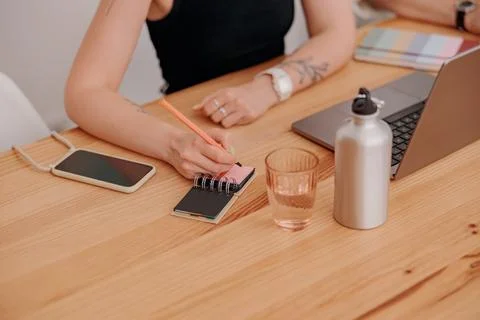 Close up of woman freelancer making notes during work in cozy coworking Stock Photos