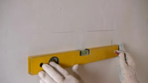 Close-up of a woman in gloves using a construction level and a pencil to mark Stock Footage 302285481