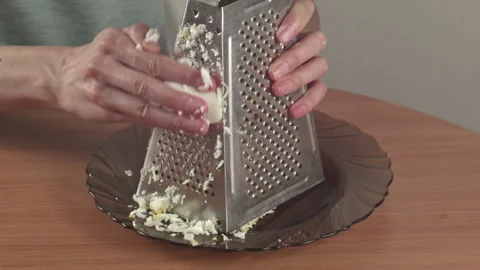 Close-up of woman grating a boiled egg on a metal grater at a kitchen table Vídeo Stock 314859552