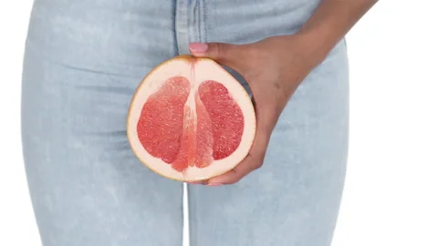 Close-up of a woman hand holding a half of grapefruit. Fingers are touching Stock Footage 133123700