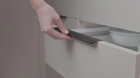Close up of woman hand pulling modern handle to open white kitchen drawer Stock Footage 329041680