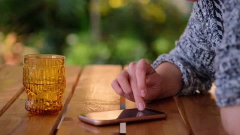 Close-up of woman hand typing message on phone over a wooden table,blurred Stock Footage 166411640