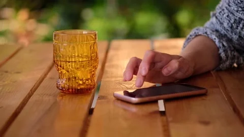 Close-up of woman hand typing message on phone over a wooden table,blurred Stock Footage 166411676