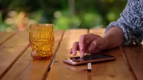Close-up of woman hand typing message on phone over a wooden table,blurred Stock Footage 166828901