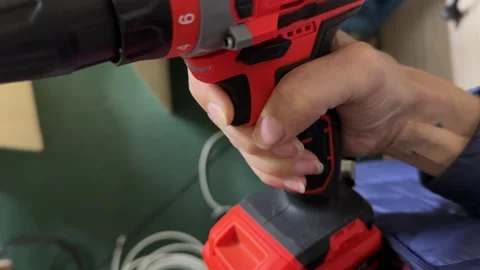 Close up of woman hand using electric screwdriver, pressing trigger and rotating Stockbeeldmateriaal 337110446