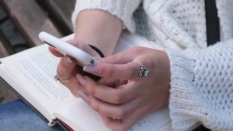Close up woman hand using smart phone with opened book Video stock 120455293