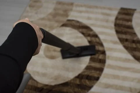 Close up of woman hand while vacuuming the carpet Stock Photos