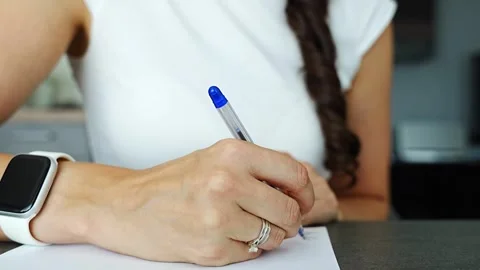 Close up of woman hand writing notes with ballpoint pen on paper in home office Stock Footage 326320707