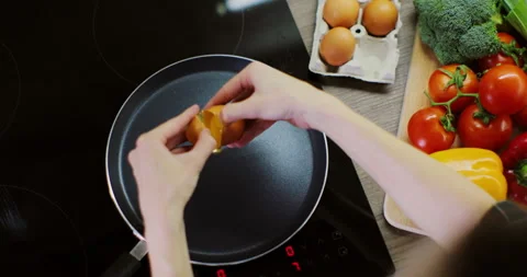 Close up woman hands cracking egg into frying pan. High angle view. Stock Footage