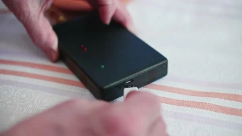 Close up of woman hands plugging USB cabel to socket of powerbank.Piece of Stock Footage 153613448