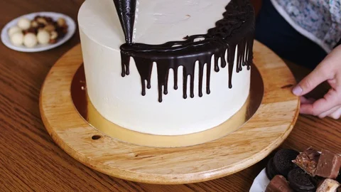 Close-up of woman hands preparing a cake pouring the chocolate cream on it Stock Footage 86320375
