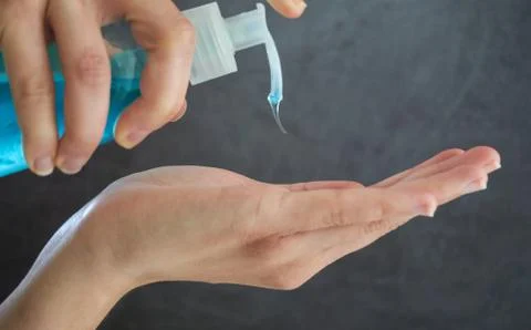 Close-up of woman hands using blue hand sanitizer gel from a clear bottle Stock Photos