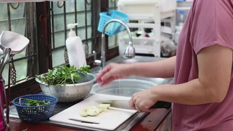 Close up of woman hands using a knife to slice fresh green eggplant. Видео 331276769