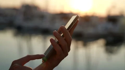 Close-up of a woman hands using a mobile phone outside in the setting sun Stock Footage 157671609