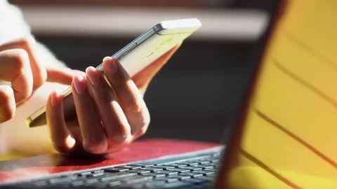 Close up woman hands using smartphone and computer laptop at workplace or work Stock Footage 129244693