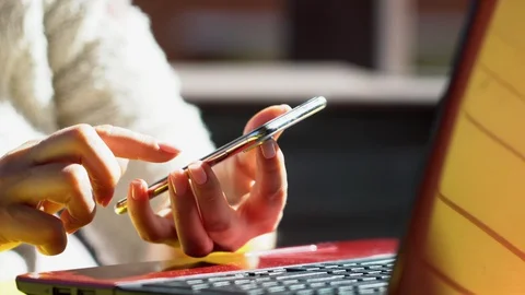 Close up woman hands using smartphone and computer laptop at workplace or work Stock Footage 129538369