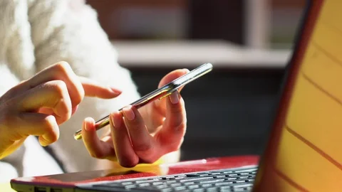 Close up woman hands using smartphone and computer laptop at workplace or work Stock Footage 130048869