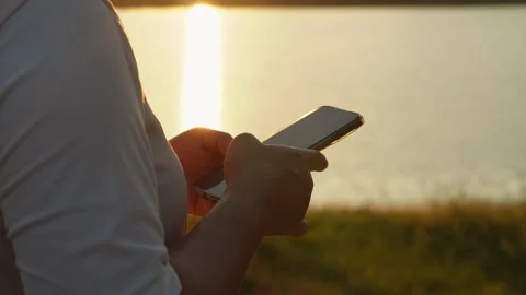 Close up of woman hands using smartphone outdoors at sunset 動画素材 327248199