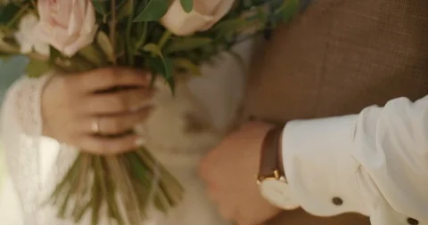 Close up of woman hands with wedding ring and a bouquet. Groom hugs his bride Stock Footage 123799794