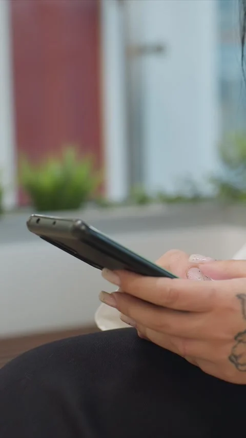 Close up of woman holding and using smartphone with tattoo on hand in soft Stock Footage 344669166