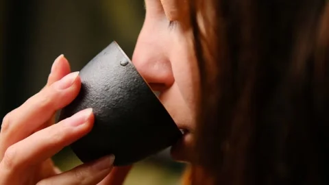 Close-Up of a Woman Lips Drinking Tea from a Black Ceramic Cup During a Tea Stock Footage 295780337