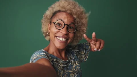Close-up, woman looking at camera, taking selfie, gesturing victory isolated on Stock Footage 252505126
