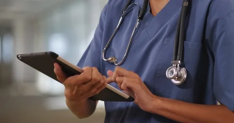 Close up of woman nurse or doctor working on table computer inside hospital Stock Footage