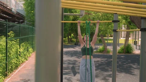 Close up of woman performing assisted pull ups with resistance bands outdoors in Stock Footage 345844948