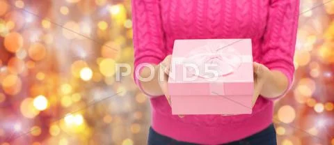 Close up of woman in pink sweater holding gift box Stock Photos