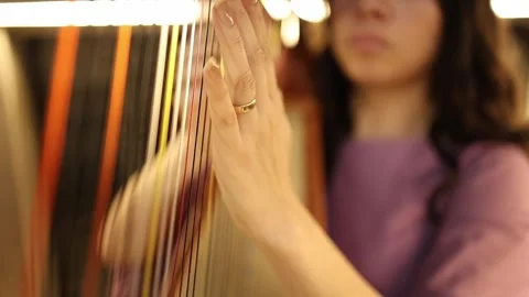 Close-up of Woman Playing Harp Strings in Warm Lighting Stock Footage 340558824