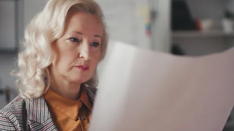 Close-up of woman property developer examining building blueprint in her office Stock Footage 256326618