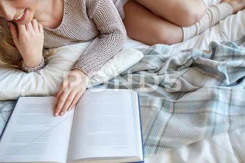 Close up of woman reading book in bed at home Stock Photos