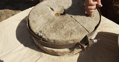 Close up. A woman rotating a hand-driven millstone, grinding wheat into flour. Stock Footage 142131985