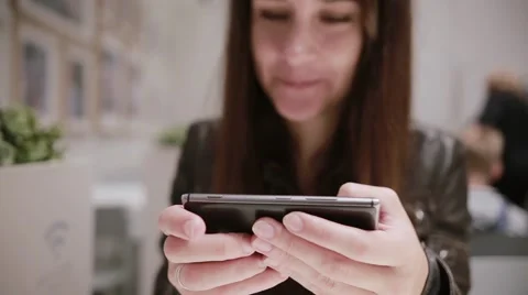 Close-up of woman s hands using a smartphone. Pretty brunette girl smiling Video stock 67947316