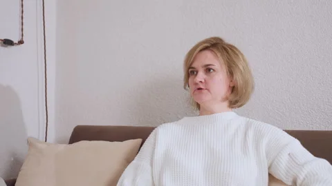 Close up of woman seated on sofa explaining thoughtfully during conversation Stock Footage 310856886