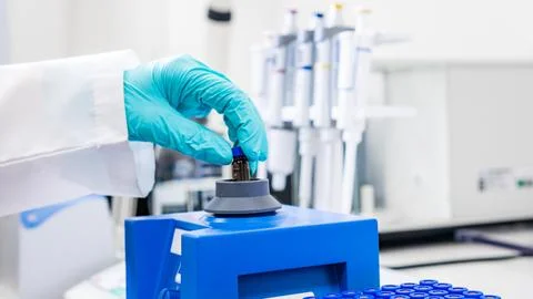 Close up of a woman shaking samples using a vortex mixer before HPLC analysis. Stock Photos