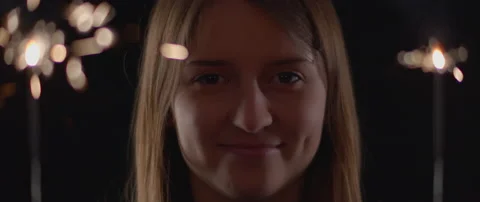 Close up of a woman smiling to the camera with two sparkles in the background Stock Footage 132962432