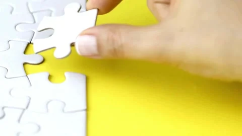 Close up of woman solving a jigsaw puzzle with abundance of pieces Completing Stock-Footage 336248643