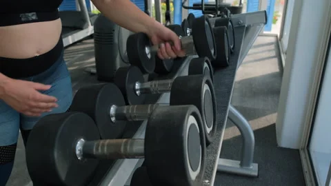 Close-up of woman taking dumbbells from the rack 動画素材 272808317