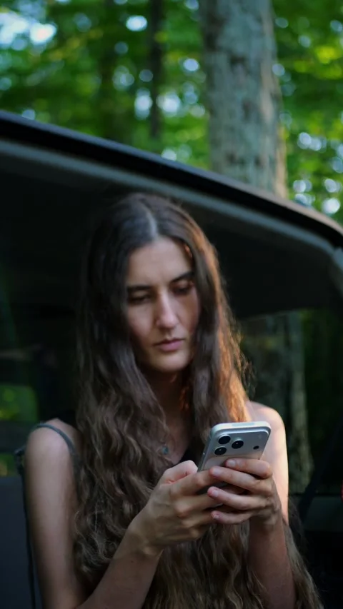 Close-up of a woman texting on a smartphone while sitting in a parked SUV... Vídeos de archivo 340291017