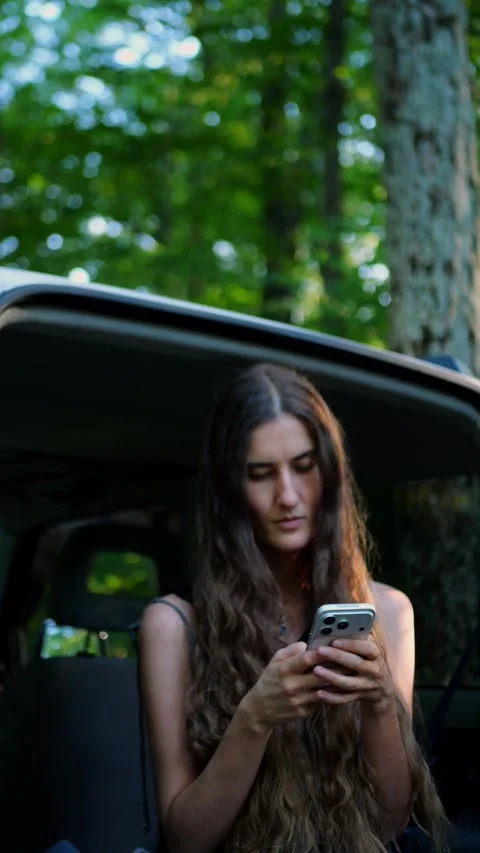 Close-up of a woman texting on a smartphone while sitting in a parked SUV. Видео 340291020