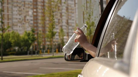 Close-up of a woman throwing a plastic bottle out of a car window. Stock Footage 210752807